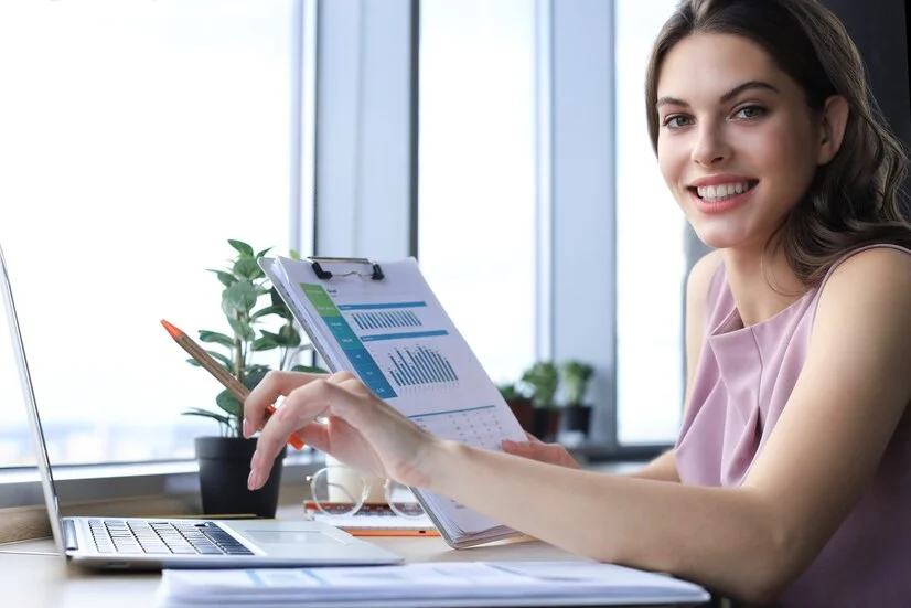 women is holding calculator and writing and working on a bookkeeping project